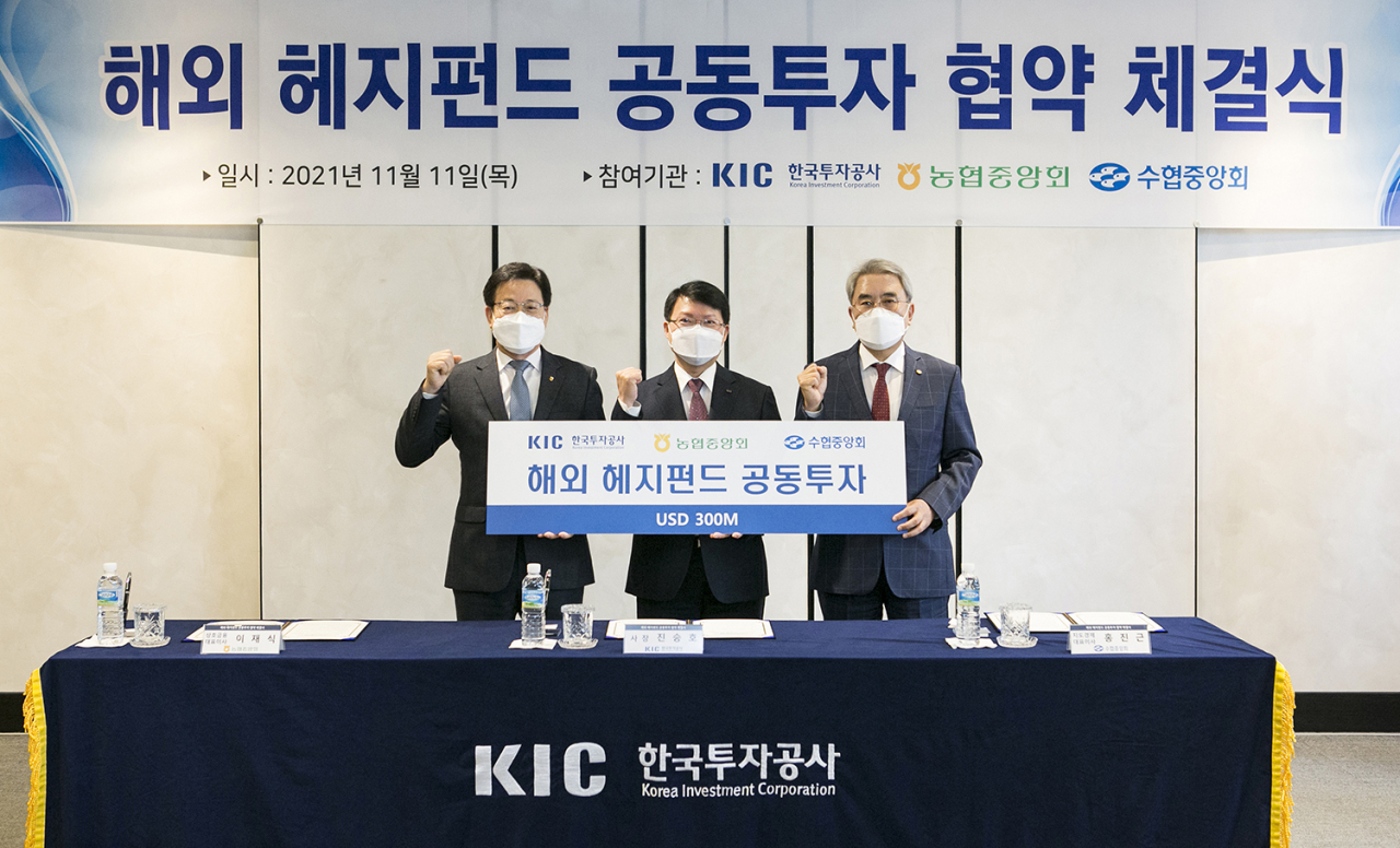 cap. From left: Lee Jae-shik, president of the National Agricultural Cooperative Federation, Jin Seung-ho, CEO of Korea Investment Corp., and Hong Jin-keun, president of the National Federation of Fisheries Cooperatives pose for a photo during a ceremony held in KIC’s headquarters in Seoul on Thursday. (KIC)