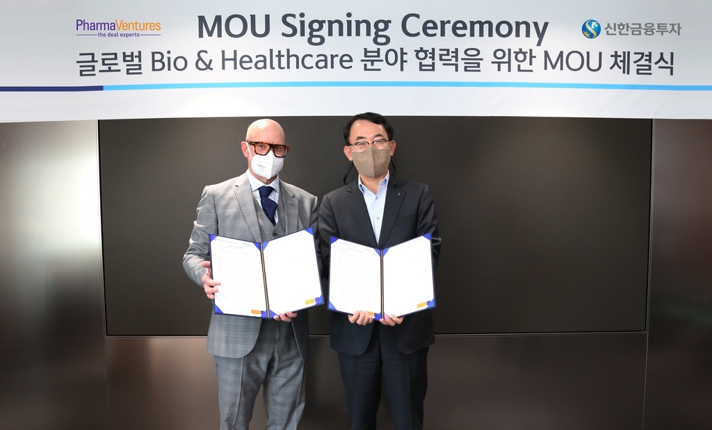 Jung Keun-soo (right), vice president of Shinhan Investment’s global investment banking division, poses for a photo with Adrian Dawkes, managing director at PharmaVentures, after signing a strategic partnership for cooperation in various investment banking and consulting services to expand South Korean pharmaceutical companies’ global market entry. (Shinhan Investment)