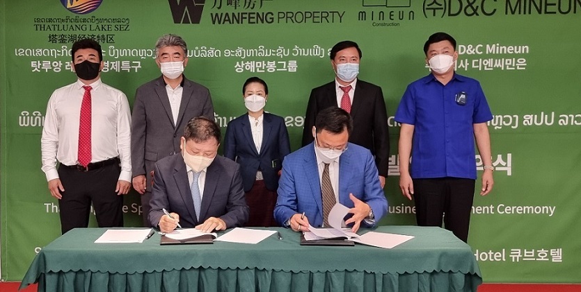 Yang Young-hwan (front left), chairman of D&C Mineun, and Jian Fu (front right), president of Wanfeng Property, sign an agreement for joint development of the Thatluang Lake Special Economic Zone in Laos, with Jungheung Vice Chairman Jung Won-ju (back row, second from left) and Khamchan Vongsenboun (back row, center), vice minister of planning and investment, observing the ceremony held in Vientiane, Laos, Tuesday.
