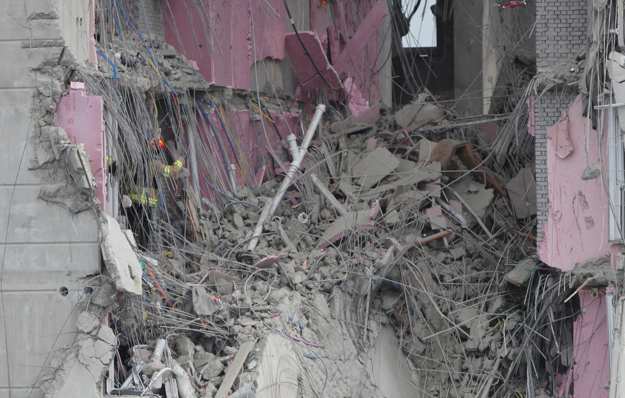 Rescuers comb through debris on Thursday, looking for workers who went missing in a deadly apartment construction accident in the southern city of Gwangju. (Yonhap)