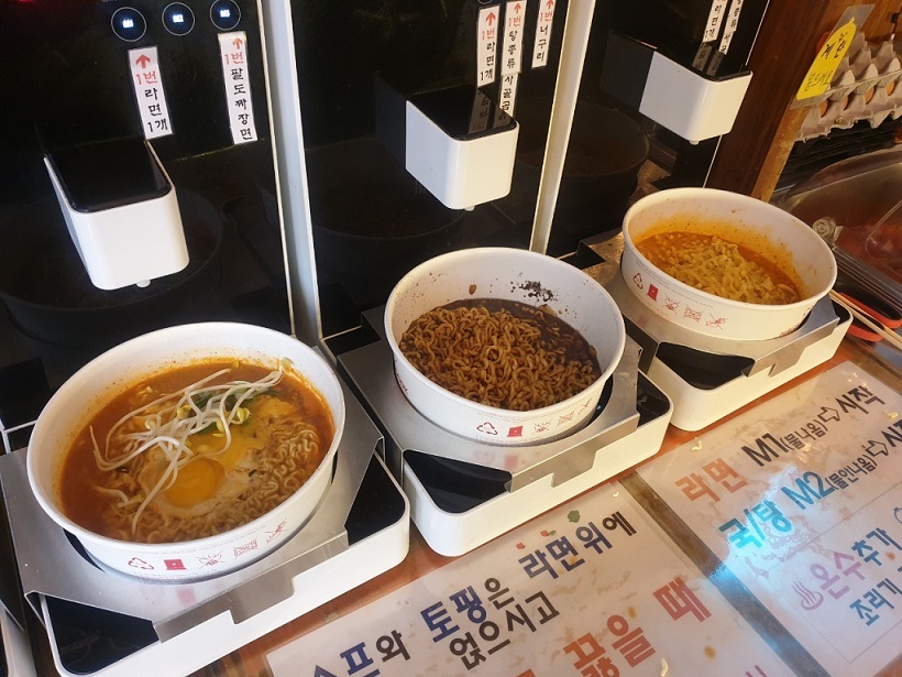 The instant noodles are placed in three different paper containers in specialized cooking machines.  (Choi Jae Hee/The Korea Herald)