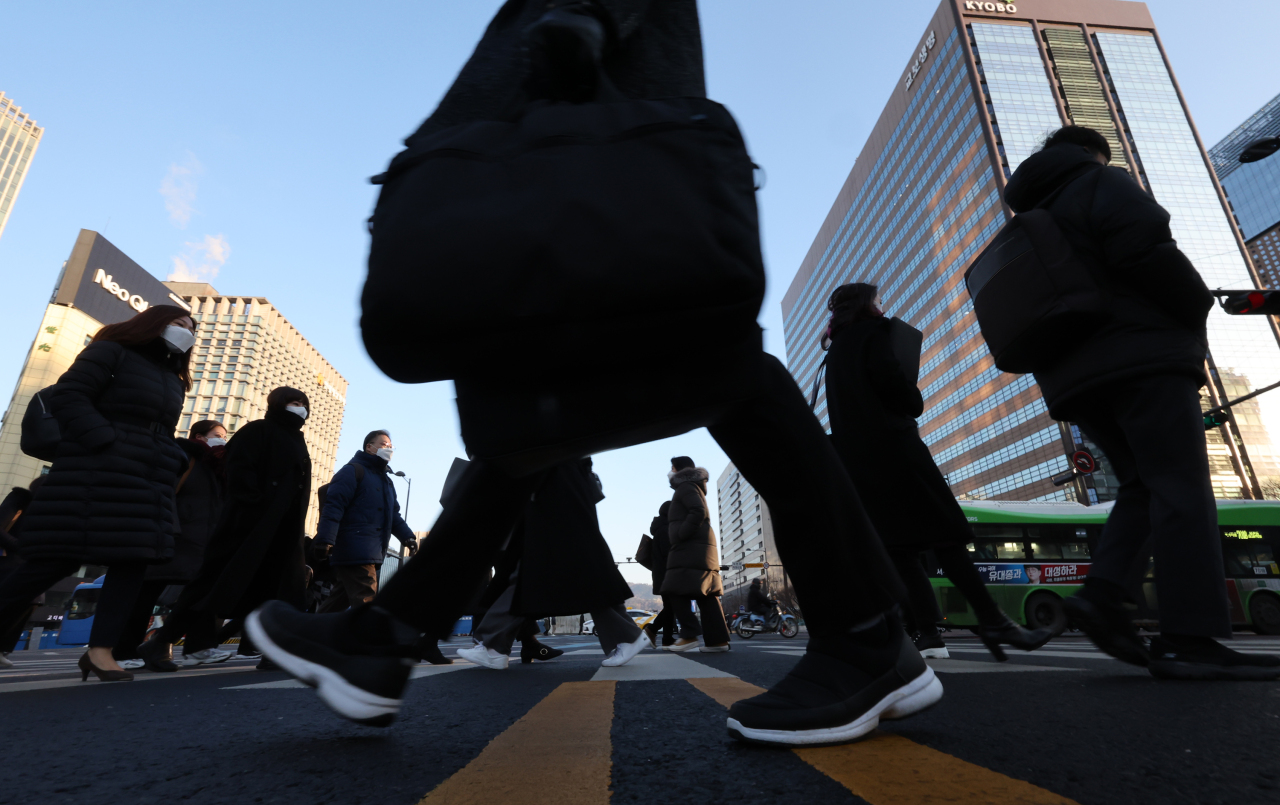 Morning commuters in face masks walk across pedestrian crosswalk in Gwanghwamun, central Seoul, on Thursday. (Yonhap)