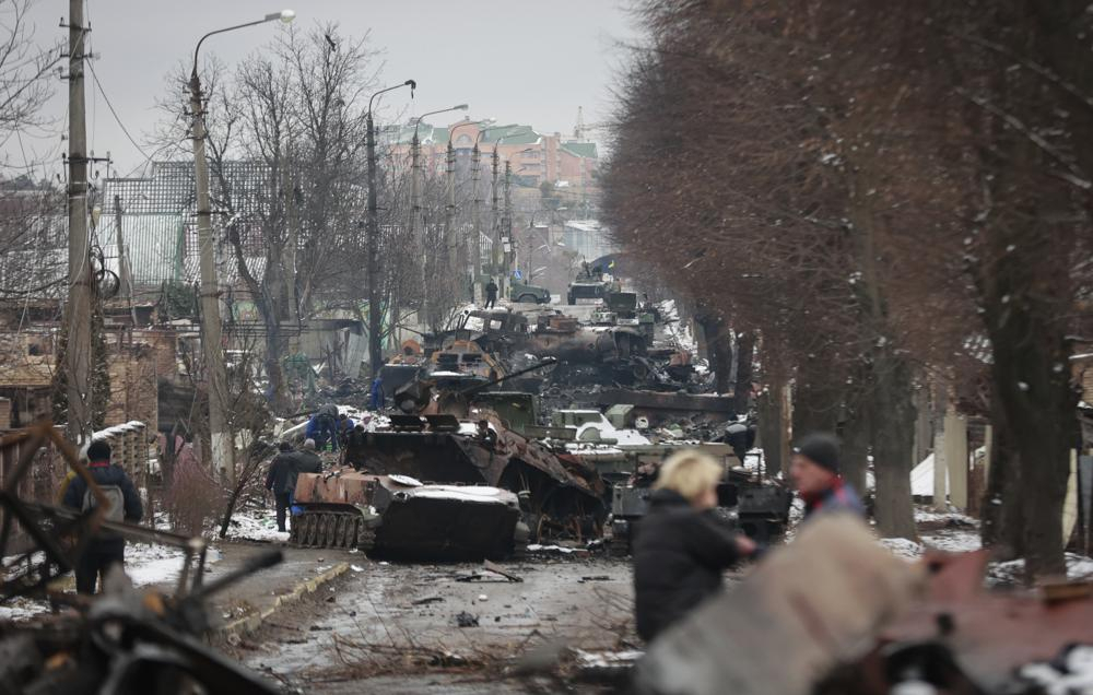 People look at the gutted remains of Russian military vehicles on a road in the town of Bucha, close to the capital Kyiv, Ukraine on Tuesday. Russia on Tuesday stepped up shelling of Kharkiv, Ukraine's second-largest city, pounding civilian targets there. Casualties mounted and reports emerged that more than 70 Ukrainian soldiers were killed after Russian artillery recently hit a military base in Okhtyrka, a city between Kharkiv and Kyiv, the capital. (AP Photo/Serhii Nuzhnenko)