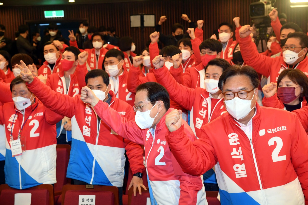 Main opposition People Power Party members raise their fists in celebration after its presidential nominee Yoon Suk-yeol took a lead in the poll as the ballot count progressed after midnight Thursday.
