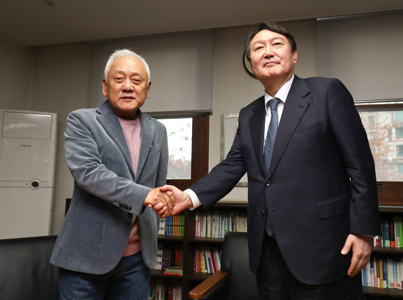 This photo provided by the National Assembly press corps shows Yoon Seok-youl (R), the presidential candidate of the main opposition People Power Party, shaking hands with Kim Han-gil at the latter's office in Seoul. (National Assembly)