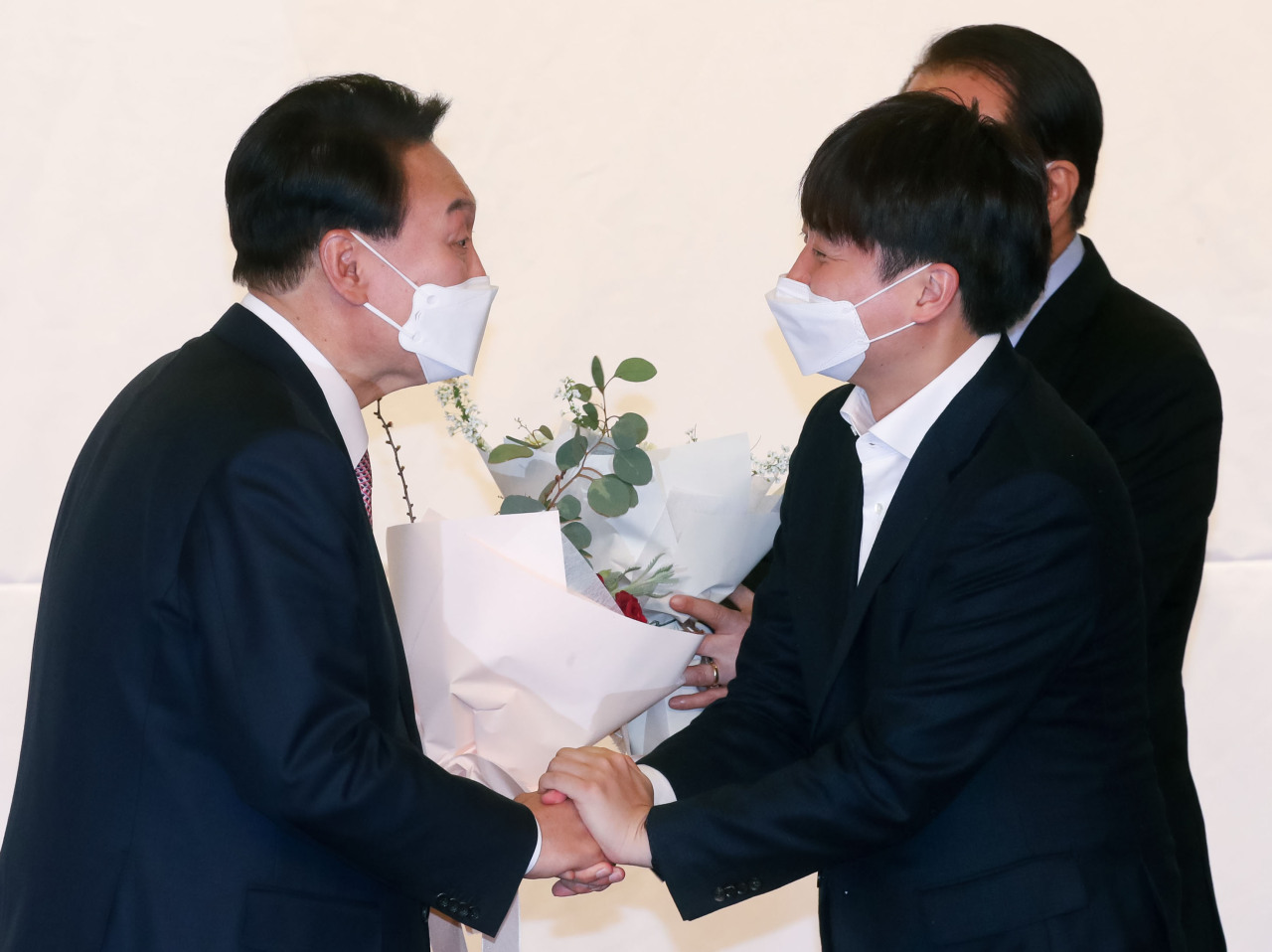 President-elect Yoon Suk-yeol (left) and People Power Party chief Lee Jun-seok exchange a handshake on March 10, a day after the election, at the National Assembly building in central Seoul. (Yonhap)