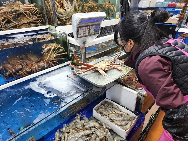 Noh, the 53 year-old owner of seafood vendor Daewon, located on the second floor of the Noryangjin fish market in Seoul, weighs a Russian snow crab. (Choi Jae-hee/The Korea Herald)