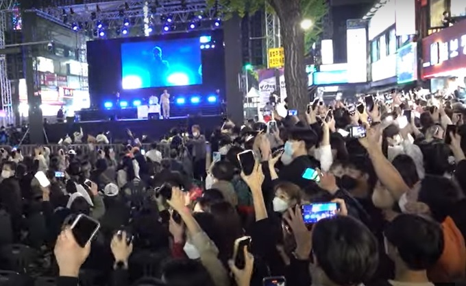 A screenshot shows the 4.19 Revolution National Cultural Festival, in which a crowd of people wave their smartphones and sing along to Korean hip-hop duo Dynamic Duo on the stage. (Courtesy of HNH TV)
