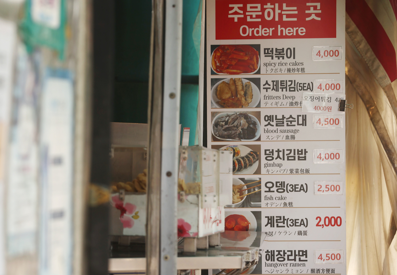 A standing signboard at a snack bar in Seoul shows hikes in price tags on food. (Yonhap)