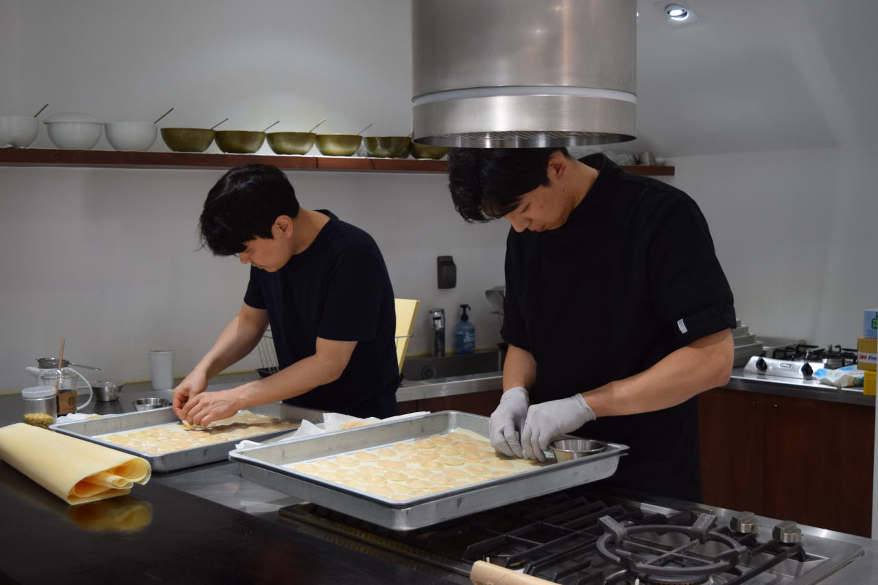 Apprentice chefs prepare scallops for a seasonal dish at Mijeoggamgag. (Kim Hae-yeon/ The Korea Herald)