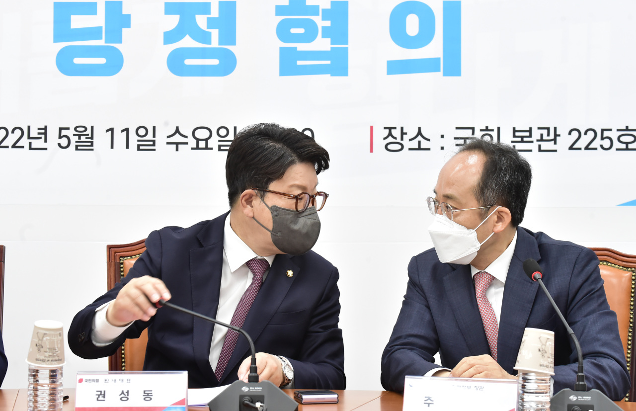 People Power Party floor leader Kweon Seong-dong (left) talks with Deputy Prime Minister and Finance Minister Choo Kyung-ho during a meeting to discuss details on a supplementary budget at the National Assembly in Seoul, Wednesday. (Yonhap)