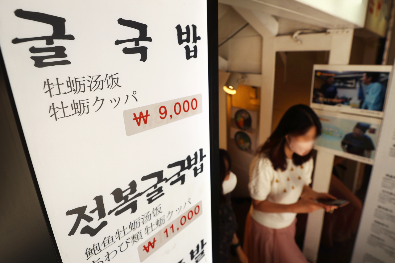 Stickers, attached on the standing signboard at a restaurant in Seoul on Friday, suggest recent hikes in price tags on food amid high inflation. (Yonhap)