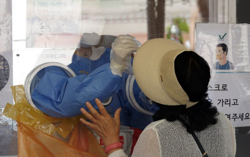 A medical worker conducts a COVID-19 test at a screening clinic in front of Seoul Station on Monday. (Yonhap)