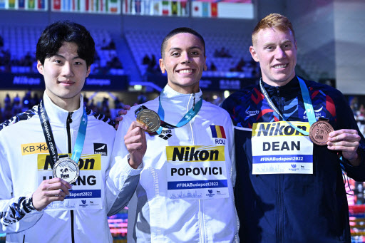 In this AFP photo, Hwang Sun-woo of South Korea (L) poses with his silver medal from the men's 200m freestyle at the FINA World Championships at the Duna Arena in Budapest on Monday. Hwang stands next to gold medalist, David Popovici of Romania (C), and bronze medalist, Tom Dean of Britain. (AFP)