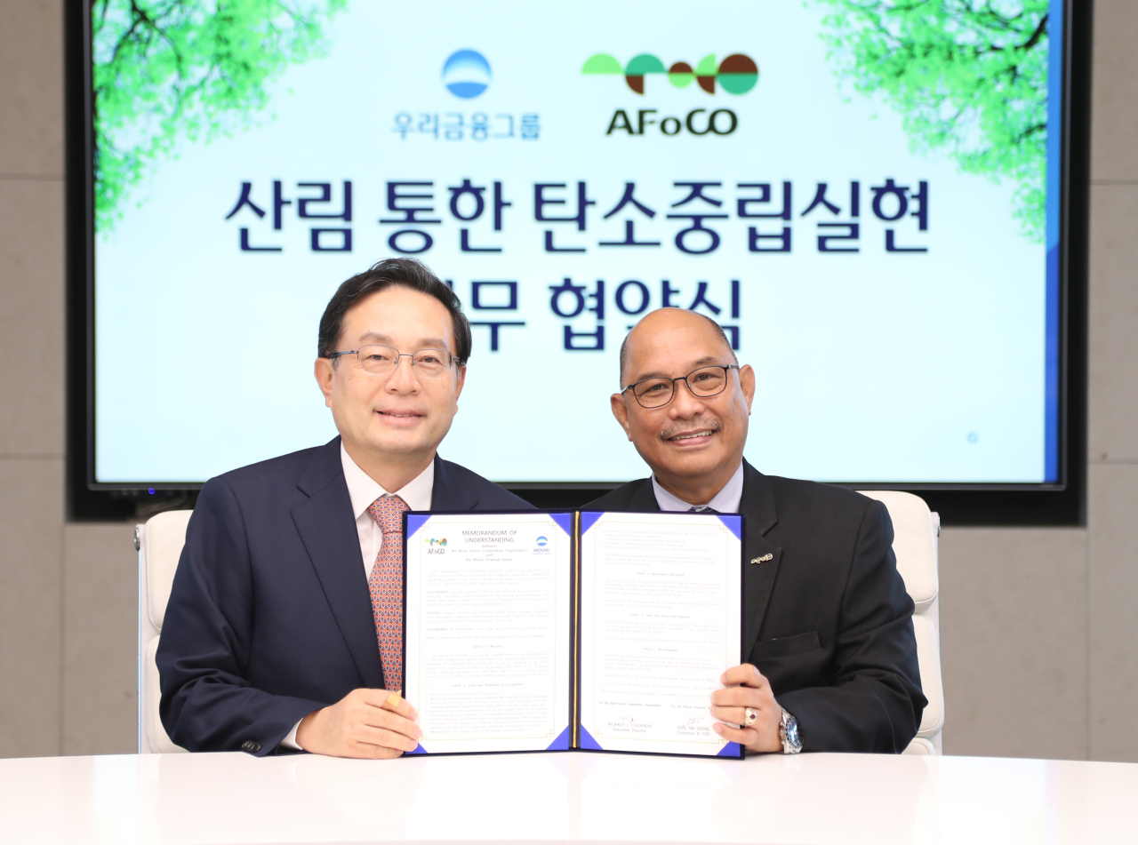 Woori Financial Group chairman Sohn Tae-seung (left) and Ricardo Calderon, executive director of Asian Forest Cooperation Organization show an agreement signed on forestry cooperation in Seoul on Tuesday. (AFoCO)