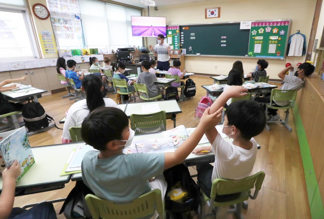 Students sit at desks that no longer have plastic dividers meant to stop spread of the coronavirus at an elementary school in Chuncheon, Gangwon Province, on Tuesday. (Yonhap)