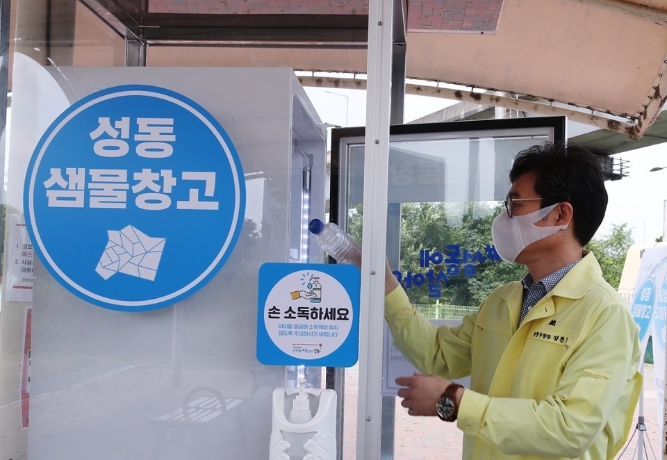 Jeong Won-oh, Mayor of Seongdong District, takes a bottle of water out of a refrigerator which has been set up as part of his district‘s scheme to counter the heat. (Seongdong District)