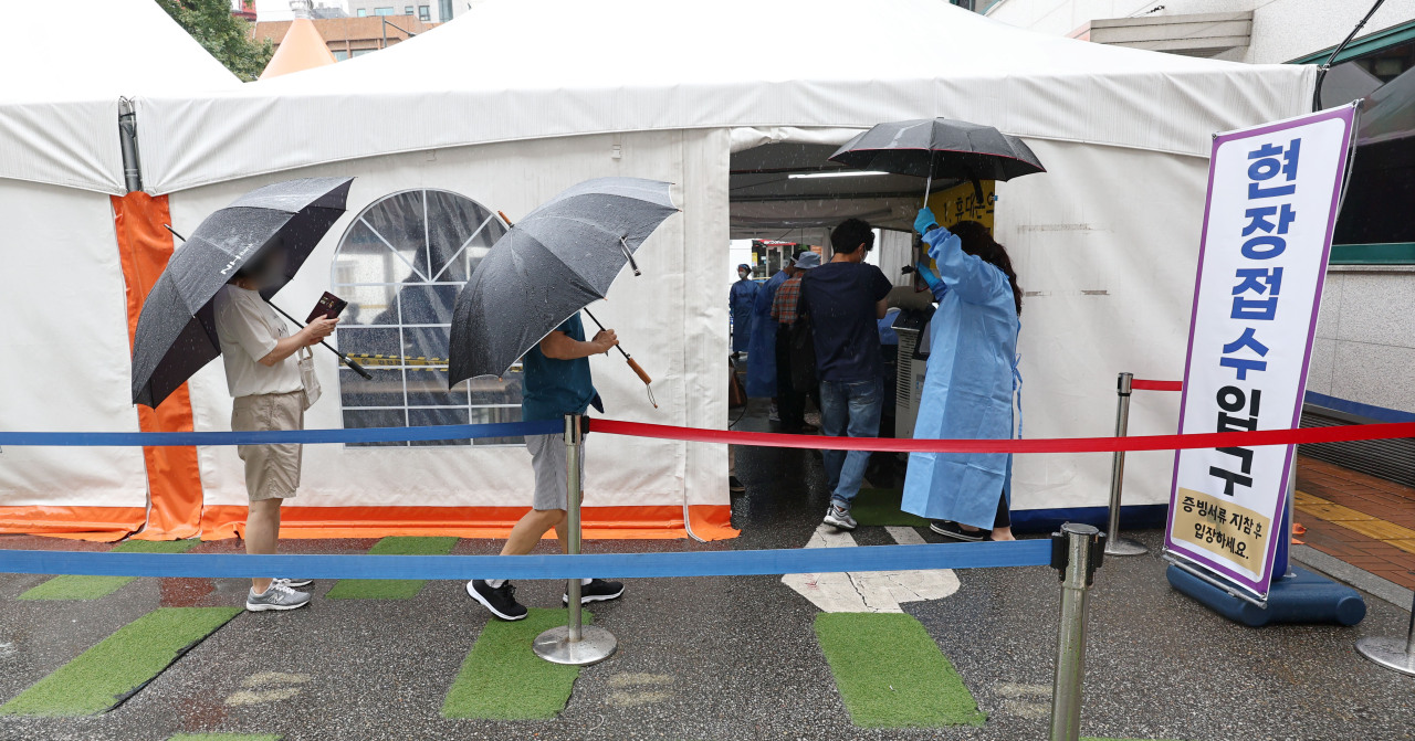 People line up to be tested of COVID-19 at a testing booth in southern Seoul, Thursday. (Yonhap)