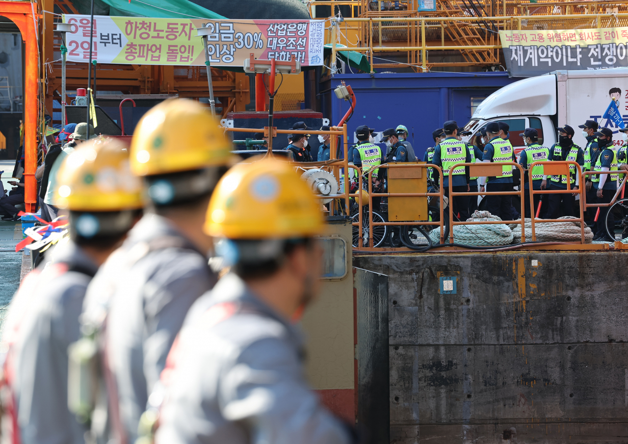 Workers of Daewoo Shipbuilding & Marine Engineering Co. watch police move around striking subcontract workers at the company's Okpo shipyard on Geoje Island, southeastern South Korea, on Friday. (Yonhap)