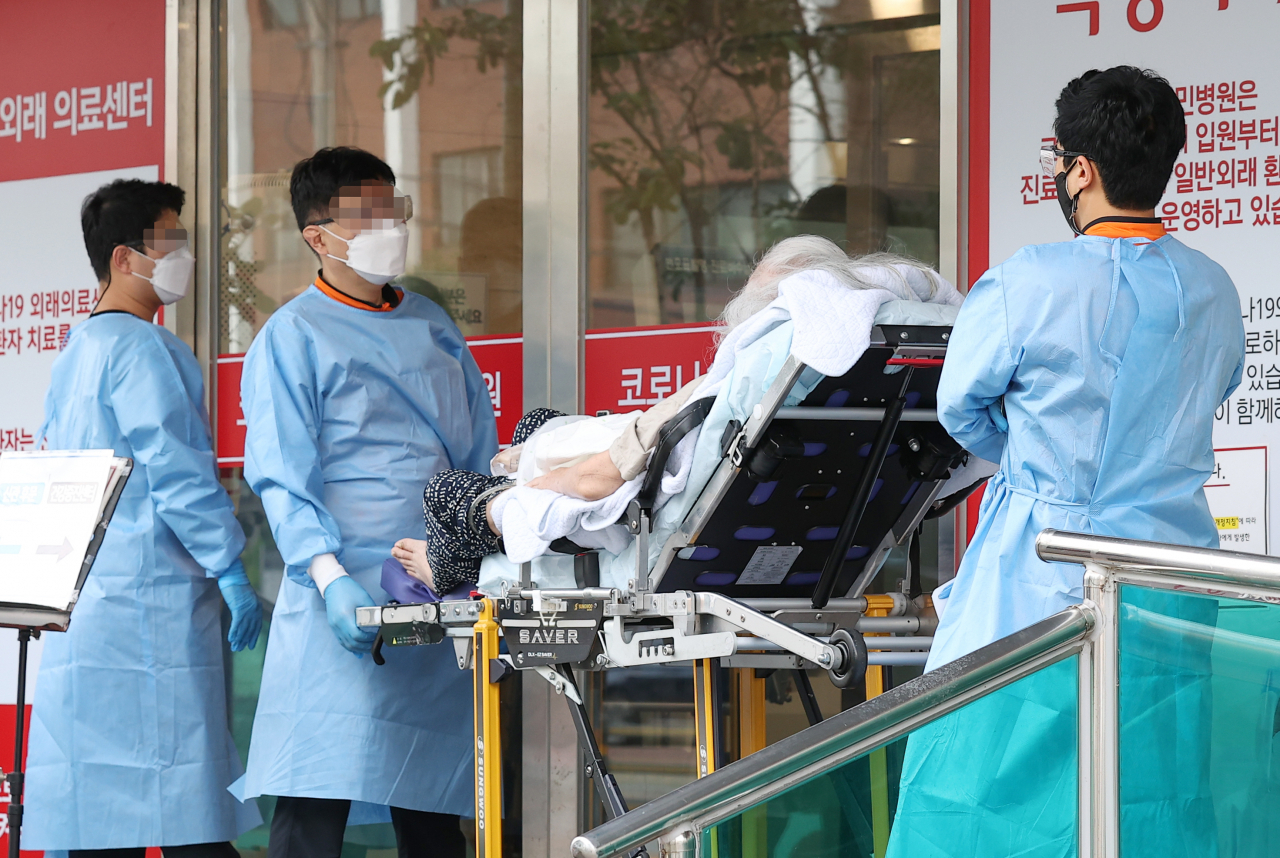 Paramedics carry a COVID-19 patient on a stretcher at a hospital in eastern Seoul on Tuesday. (Yonhap)