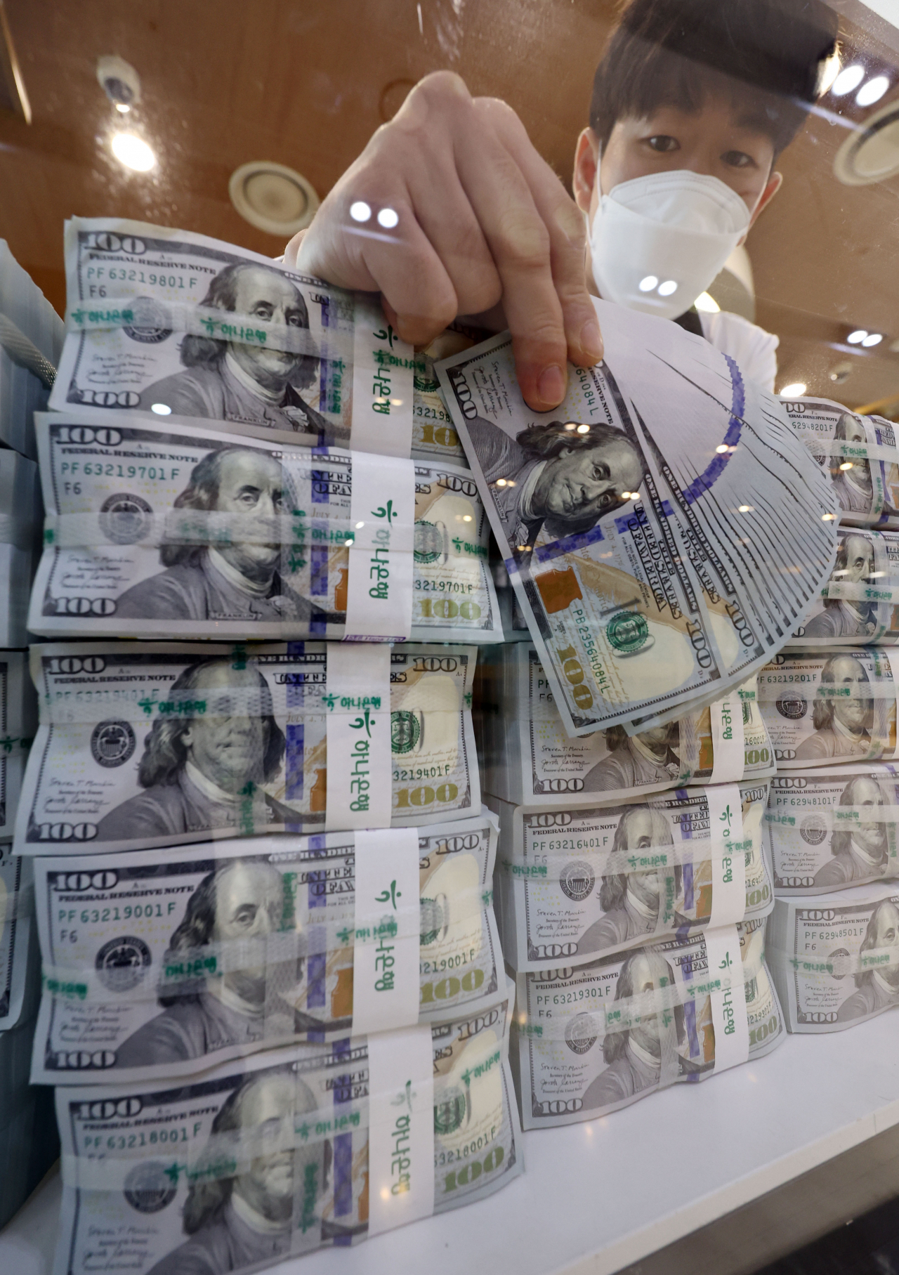 A clerk checks US dollars at the headquarters of Hana Bank in Seoul on July 5. South Korea's foreign exchange reserves dropped $9.43 billion on-month to $438.28 billion as of end-June, marking the biggest monthly decline since 2008, according to the Bank of Korea. (Yonhap)