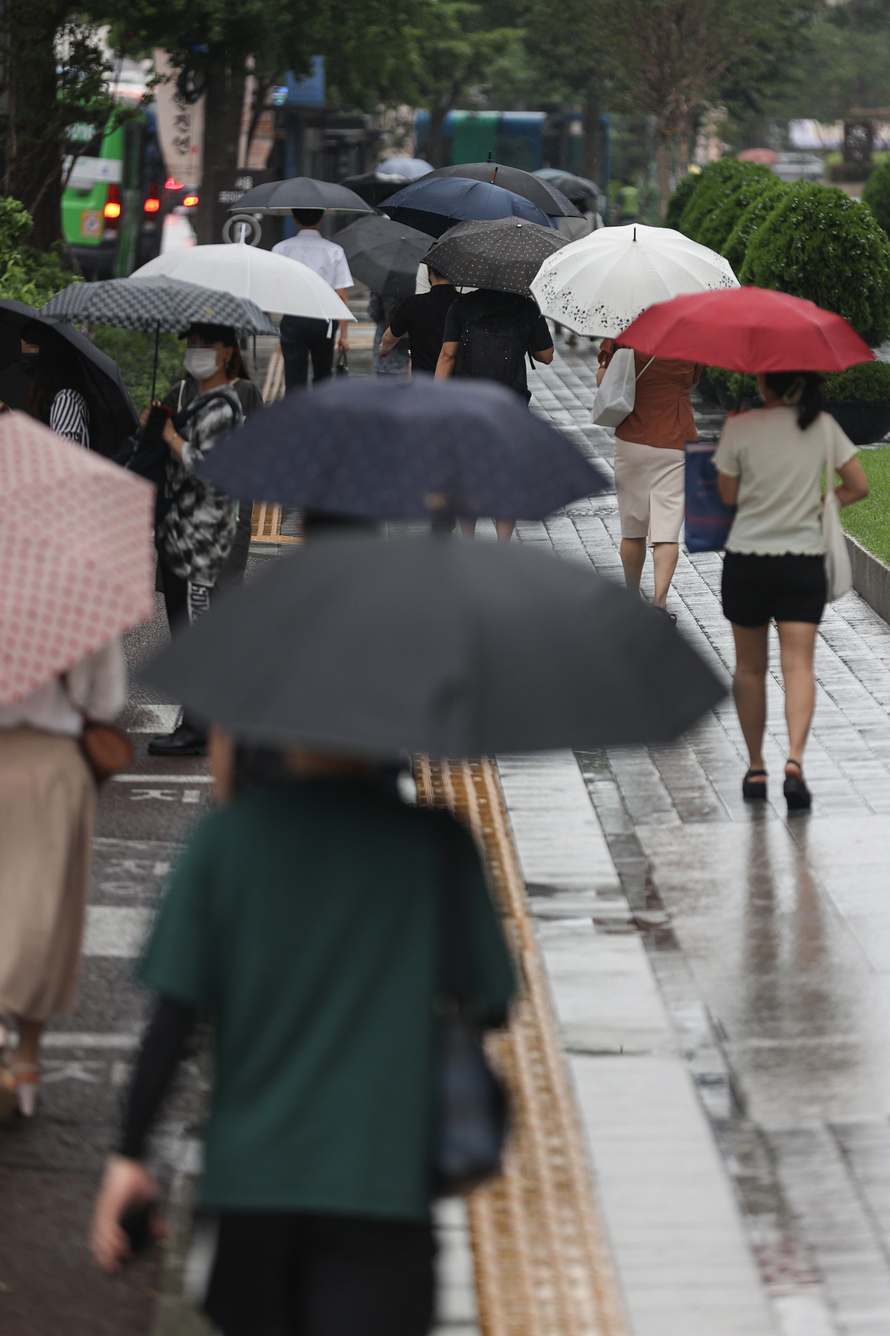 People holding umbrellas walk in the rain near City Hall in Seoul on Ju;y 13. (Yonhap)