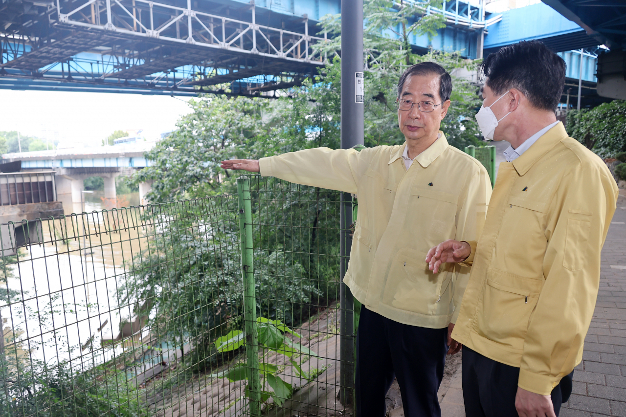 Prime Minister Han Duck-soo (L) conducts an on-site inspection of a flood control center on the Han River on Tuesday. (Yonhap)