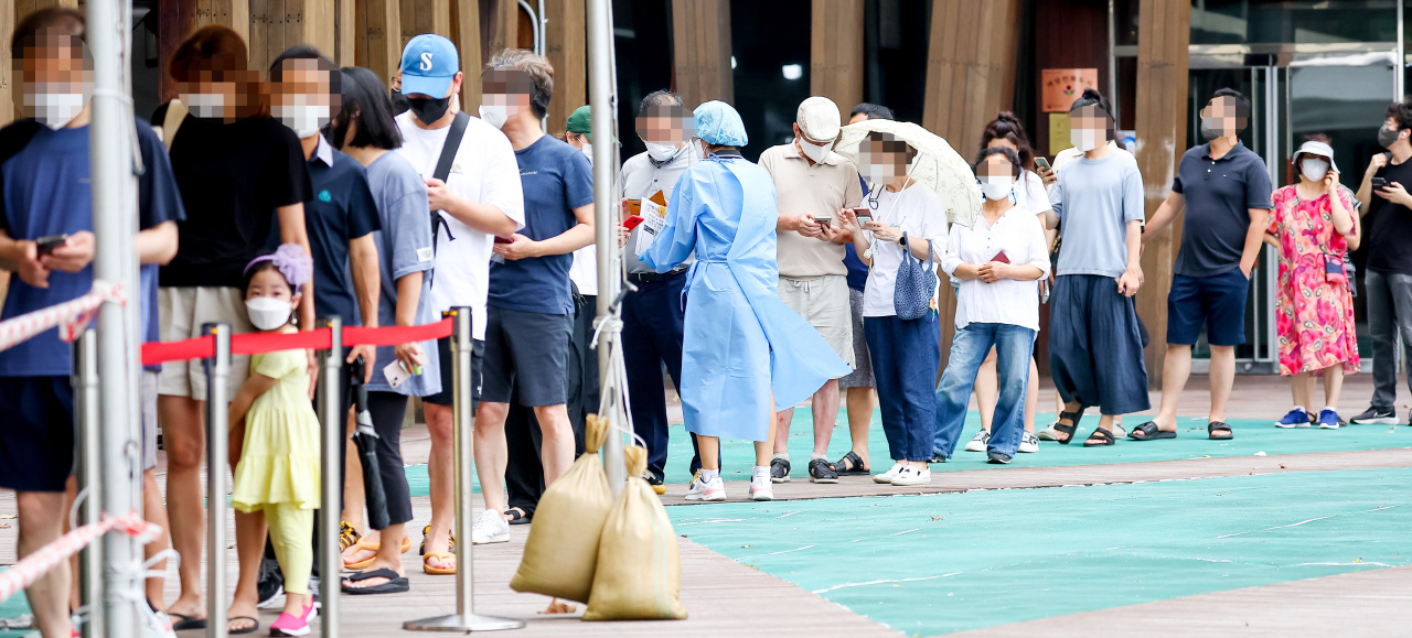 People wait in line to get COVID-19 tests at a local testing station in Songpa-gu, Seoul, Monday. (Yonhap)