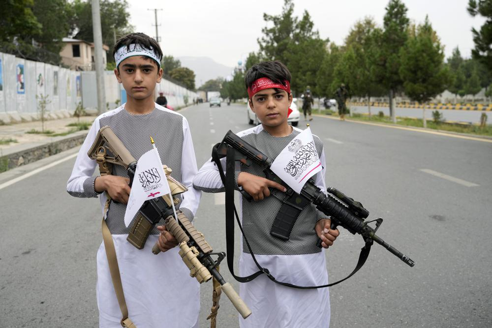 Afghan boys hold eweapons as they pose for a photo during celebrations one year after the Taliban seized the Afghan capital, Kabul, in front of the US Embassy in Kabul, Afghanistan, on Monday. The Taliban marked the first-year anniversary of their takeover after the country's western-backed government fled and the Afghan military crumbled in the face of the insurgents' advance. (AP Photo/Ebrahim Noroozi)