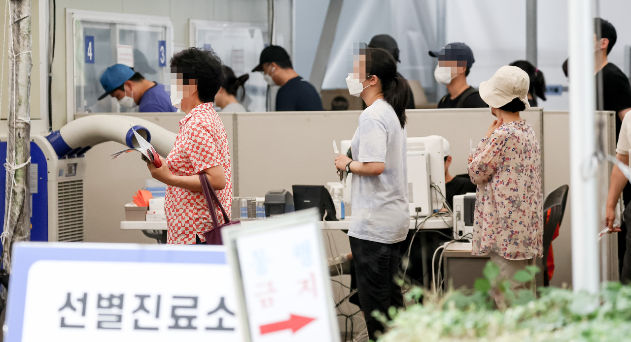 People wait in line to get COVID-19 tests at a local testing station in Songpa-gu, Seoul, Tuesday. (Yonhap)