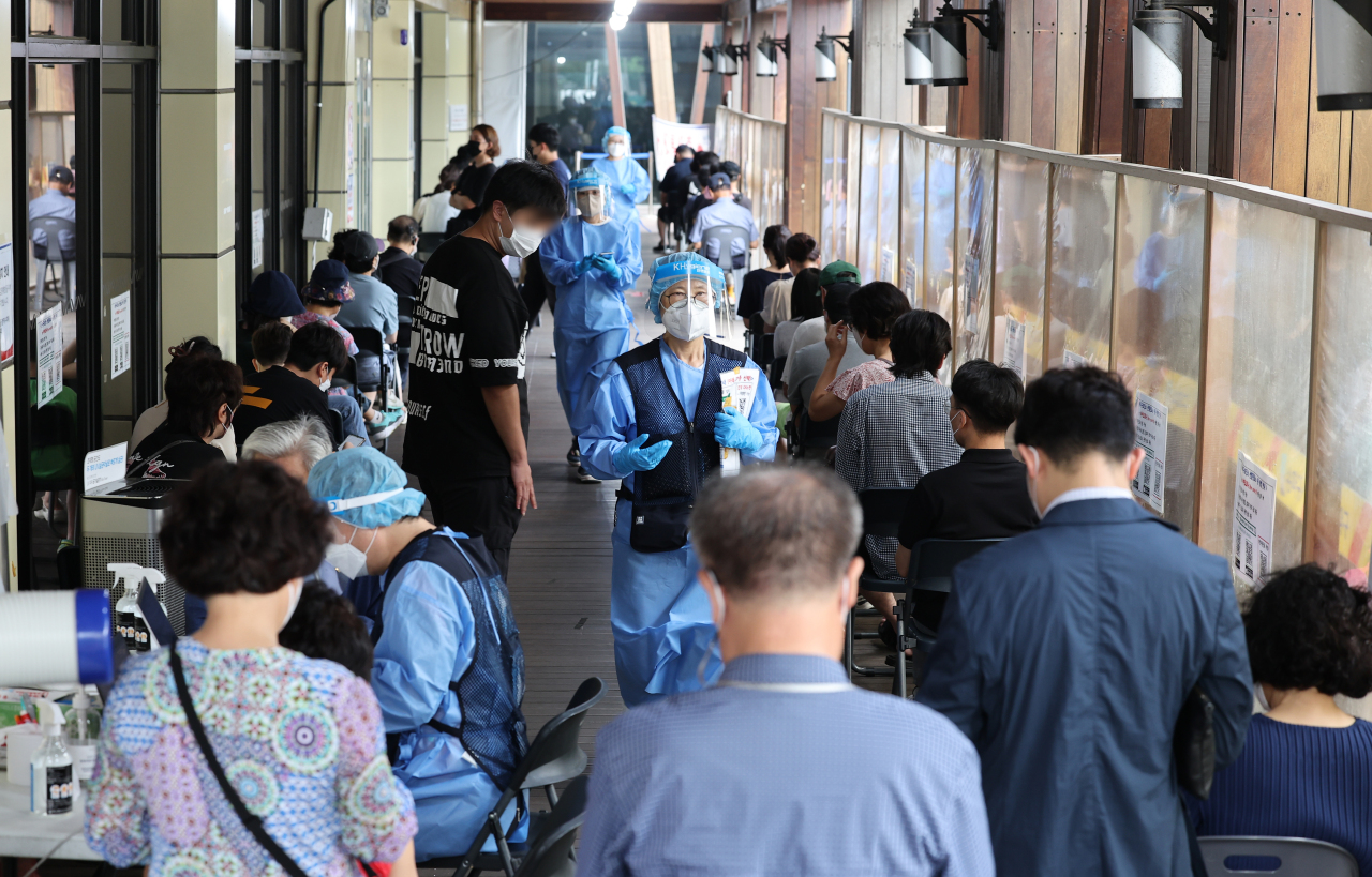People line up to get COVID-19 tests at a local testing station in Songpa-gu, Seoul, Wednesday. (Yonhap)