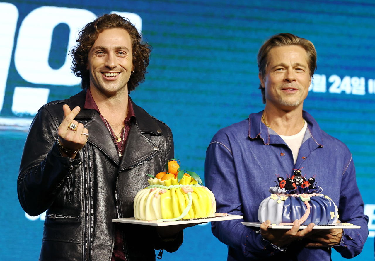 배우 브래드 피트(오른쪽)와 아론 테일러-존슨이 복주머니에 담긴 케이크를 들고 포즈를 취하고 있다. 