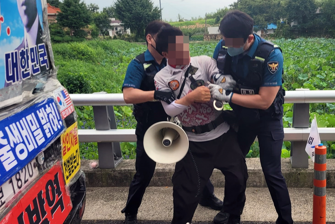 This photo captured from Facebook shows a protester being arrested by police on charges of threatening an aide to former President Moon Jae-in in front of Moon's home in Yangsan, 309 kilometers southeast of Seoul, last Tuesday. (Yonhap)