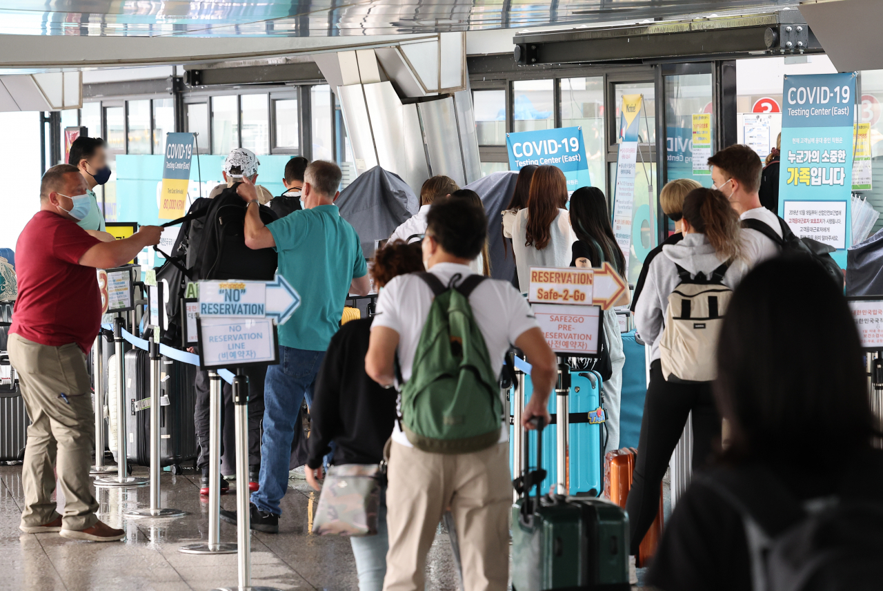 Inbound travelers from abroad stand in line to take coronavirus tests at a testing station at Incheon International Airport, west of Seoul, on Tuesday. (Yonhap)