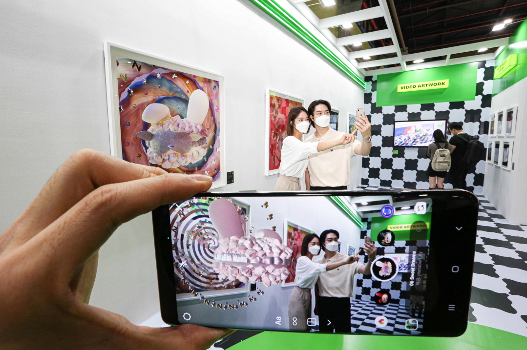 Visitors enjoy digital artworks using AR filters at the Han Sung Motor booth at Kiaf Plus in Seoul on Friday. (Han Sung Motor)