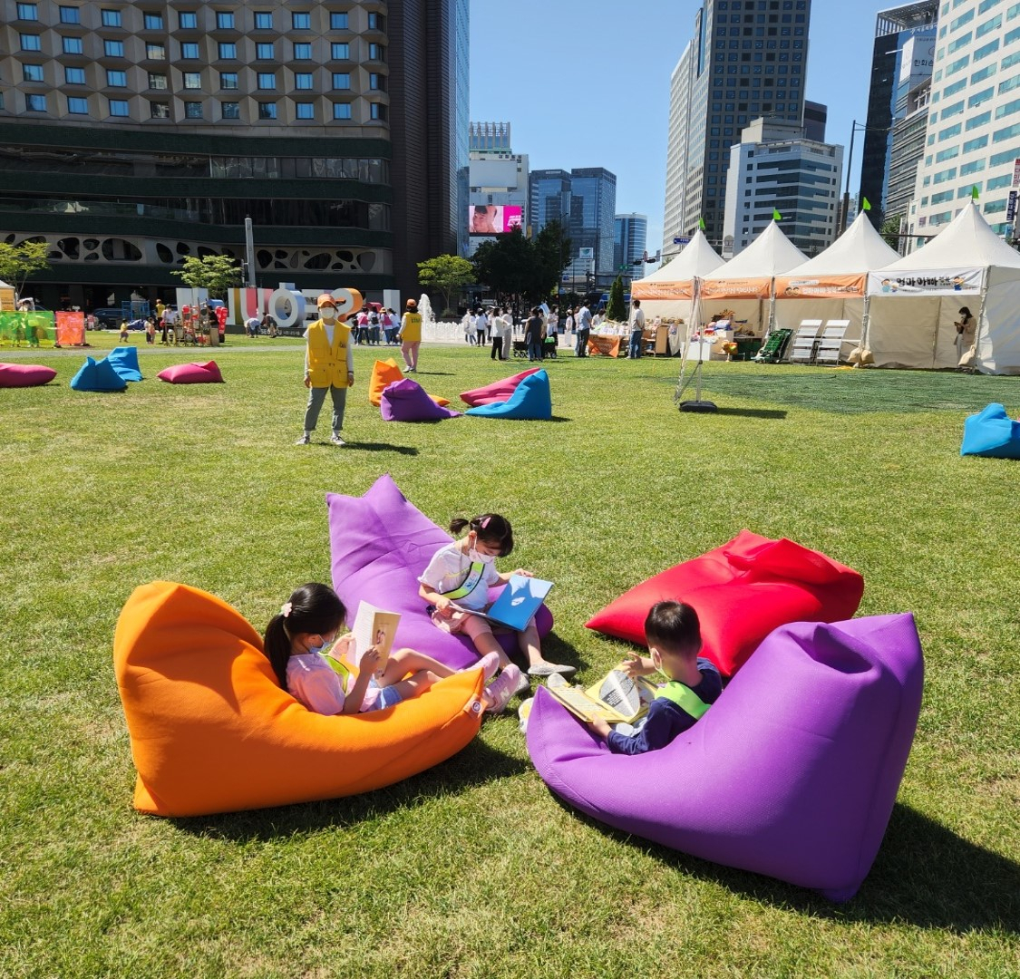 Children read books at Seoul Plaza in front of City Hall in Seoul on Sept. 2 as part of an outdoor mobile library event organized by the city government. (Choi Jae-hee / The Korea Herald)