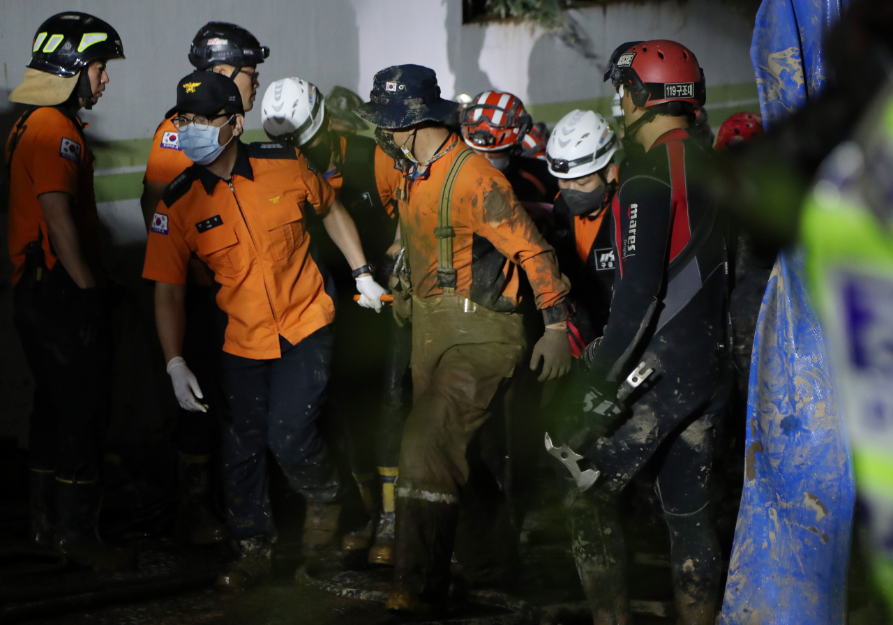 Rescue workers carry a survivor out of the flooded underground parking lot of an apartment building in Pohang, North Gyeongsang Province, southeastern South Korea, on Tuesday, after nine residents went missing following the torrential rains caused by Typhoon Hinnamnor that hit the region. (Yonhap)
