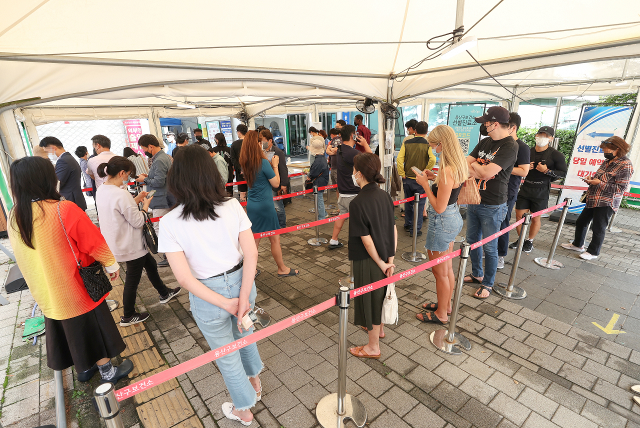 People wait in line to take COVID-19 tests at a testing booth in the community health center in Yongsan, Seoul, on Tuesday. (Yonhap)