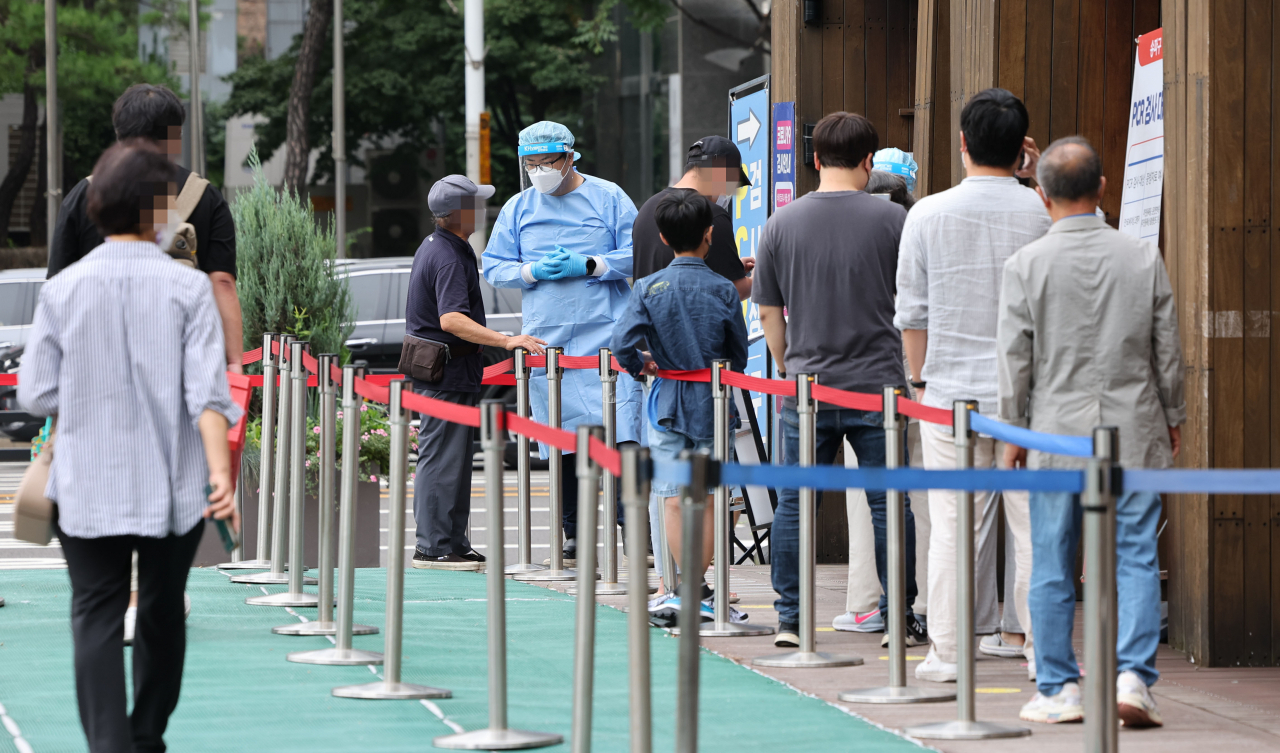 This photo taken Tuesday, shows people waiting to take a COVID-19 test at a clinic in Songpa, eastern Seoul. (Yonhap)