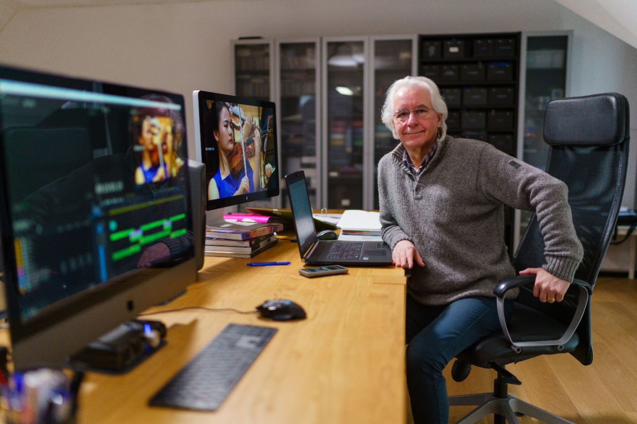 Thierry Loreau poses while editing. Shown on the screen is violinist Lim Ji-young. (Courtesy of Thierry Loreau)