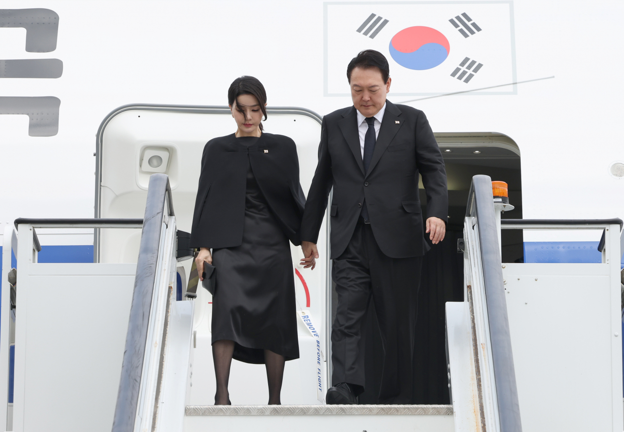 President Yoon Suk-yeol (R) and first lady Kim Keon-hee disembark from the presidential plane after arriving at London Stansted Airport on Sunday. (Yonhap)