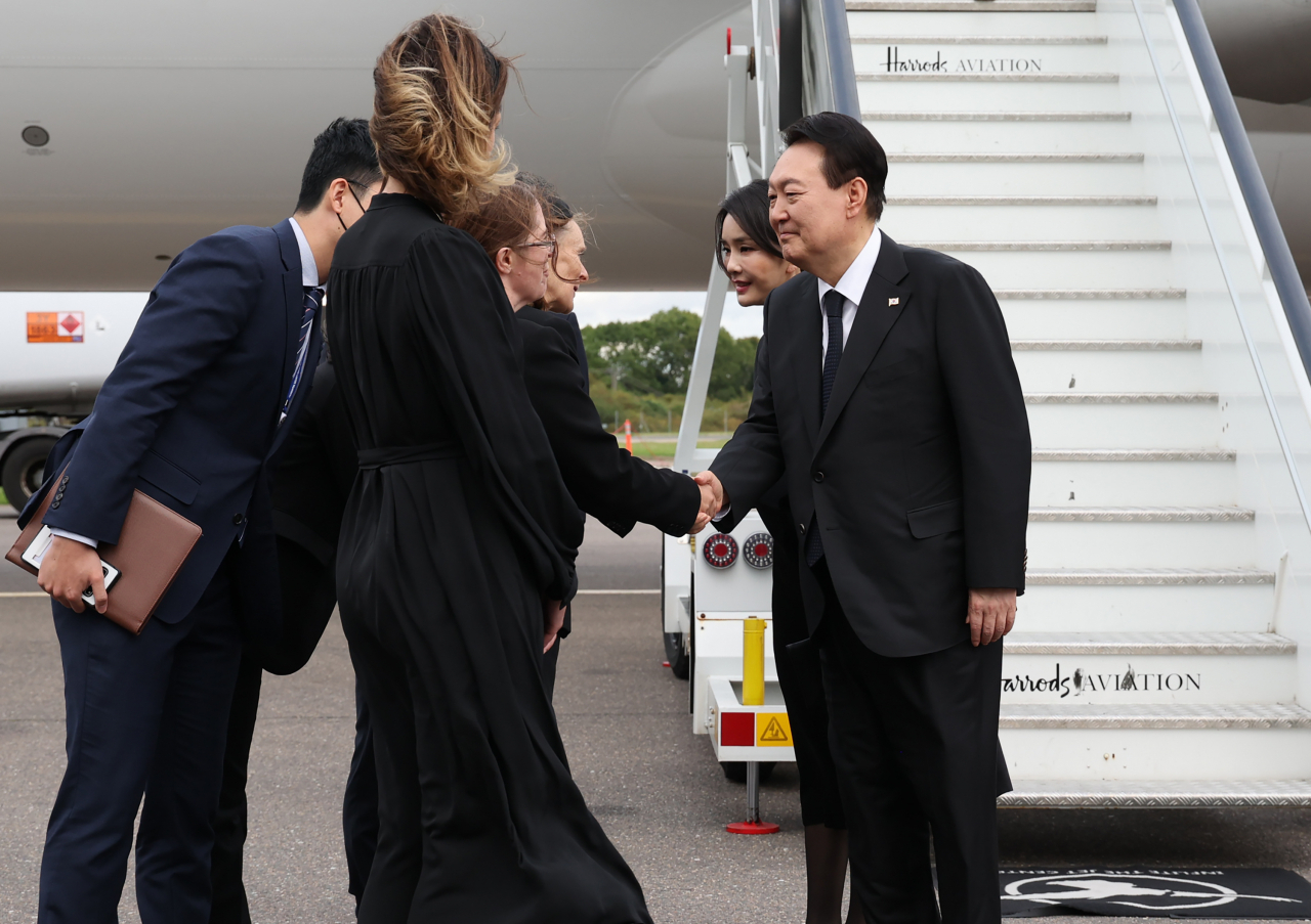 President Yoon Suk-yeol (right) and first lady Kim Keon-hee (second from right) arrive at Stansted Airport near London on Sunday. (Yonhap)