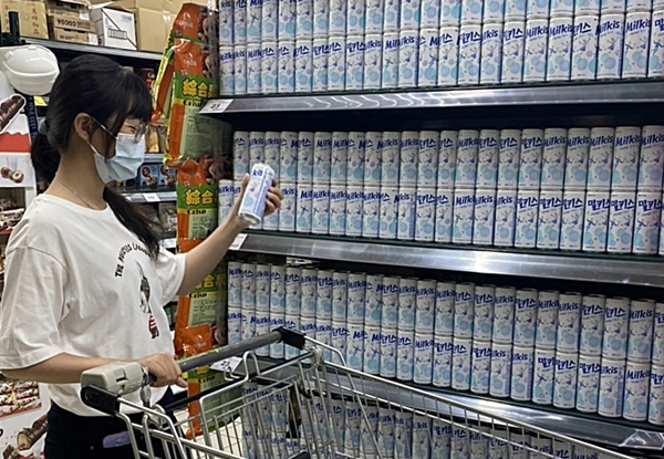 A shopper looks at a can of Milkis. (Lotte Chilsung)