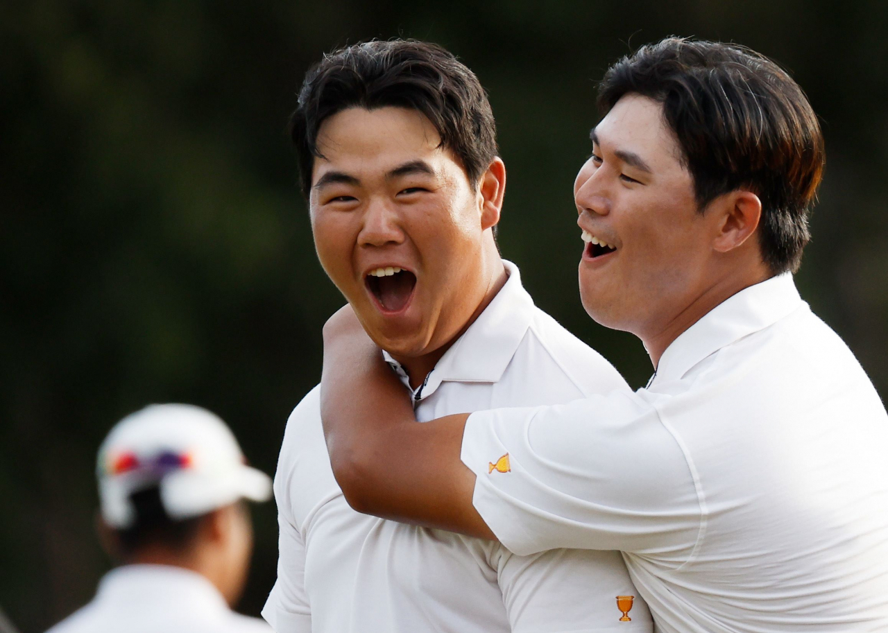 In this Getty Images photo, South Korean Kim Joo-hyung (L) is congratulated by his International teammate Kim Si-woo after making a birdie putt at the 18th hole to beat Patrick Cantlay and Xander Schauffele of the United States in their fourball match at the Presidents Cup at Quail Hollow Club in Charlotte, North Carolina, on Saturday. (Getty Images)