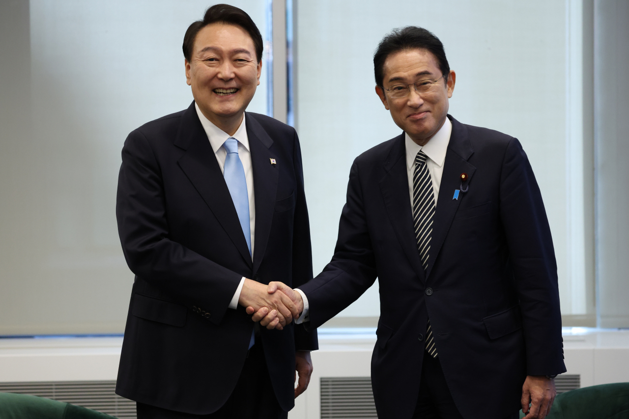 South Korean President Yoon Suk-yeol (L) and Japanese Prime Minister Fumio Kishida shake hands ahead of their summit in New York last Wednesday. (Yonhap)