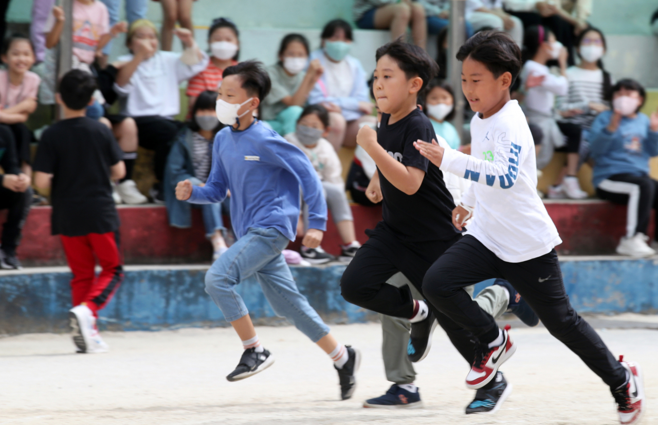 Students without masks run during a field day at an elementary school in Gwangju, 268 kilometers south of Seoul, on Monday. South Korea lifted all outdoor mask mandates the same day as the country is 