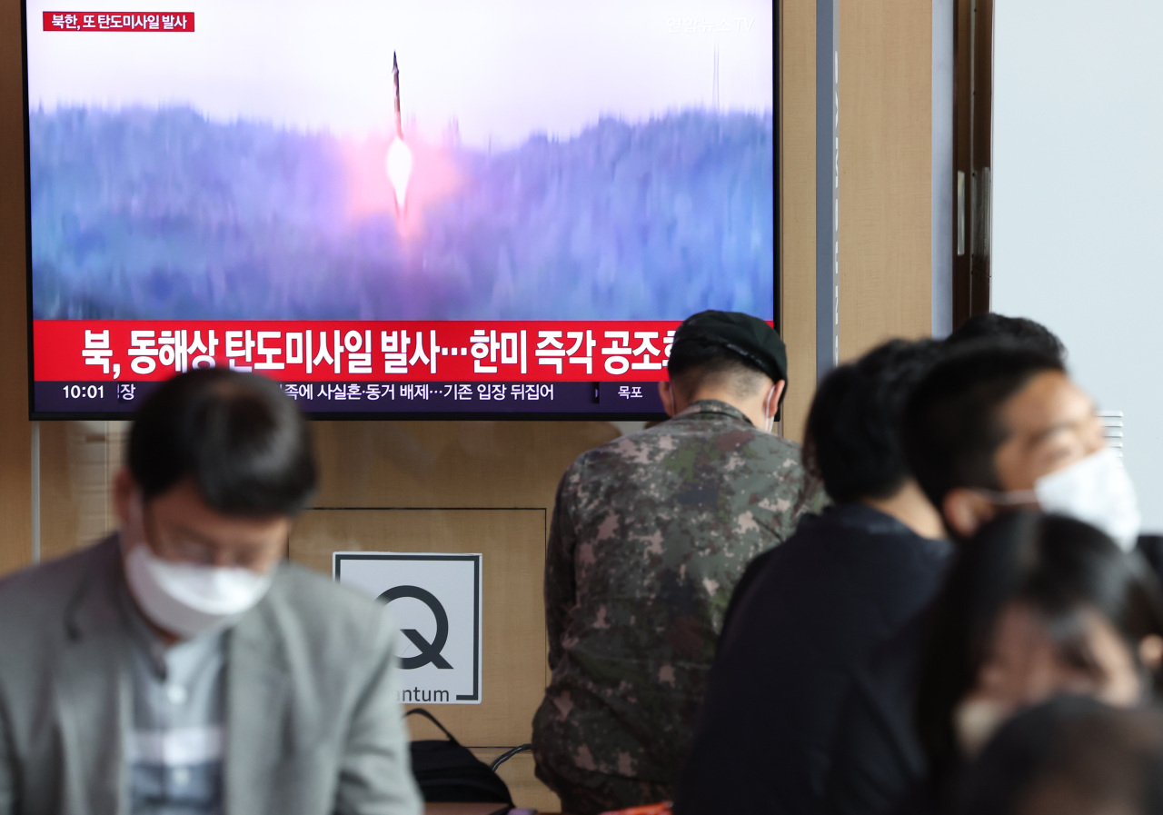 Passersby watch a TV report of North Korea’s missile launch at Seoul Station on Sunday. (File Photo - Yonhap)