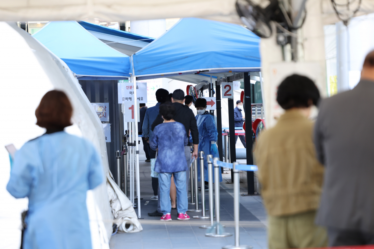 People wait to undergo COVID-19 tests at a makeshift testing station in Seoul on Tuesday. (Yonhap)