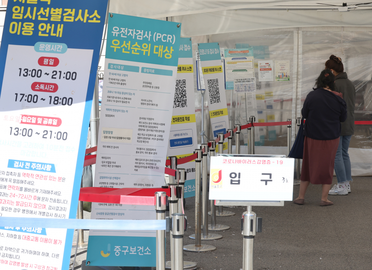 Two people wait at a coronavirus testing center near Seoul Station in central Seoul on Monday. (Yonhap)