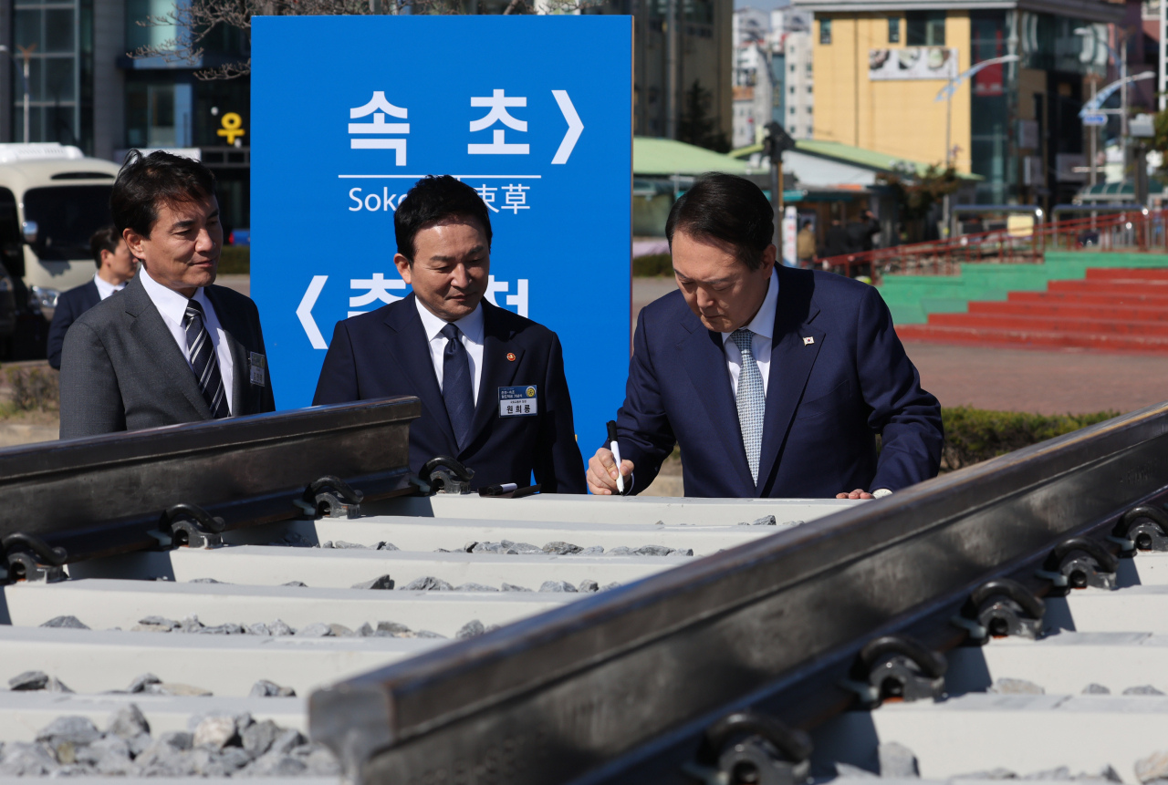 President Yoon Suk-yeol (R) signs a rail tie at the groundbreaking ceremony for the construction of an express railway connecting the northern cities of Chuncheon and Sokcho, in Sokcho, on Tuesday. (Yonhap)